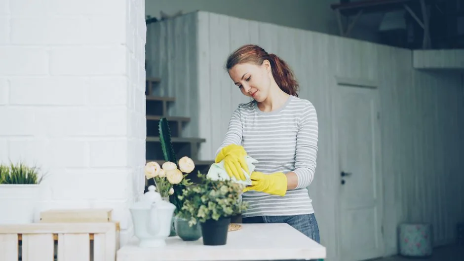 Personne anonyme portant des gants en caoutchouc jaunes et utilisant une simple éponge pour nettoyer le miroir de la salle de bain